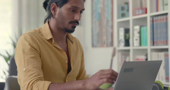 Young stressed man working with a laptop in his office at home, he is having a bad headache