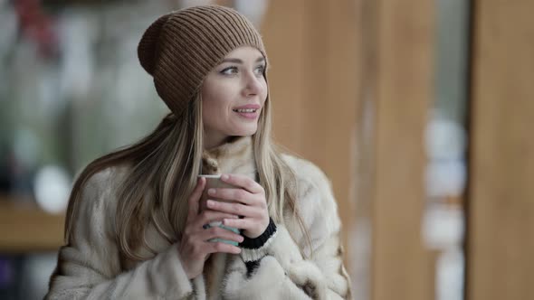 Romantic Woman Is Walking at Winter and Holding Cup of Hot Drink in Hands Coffee To Go in Street alt
