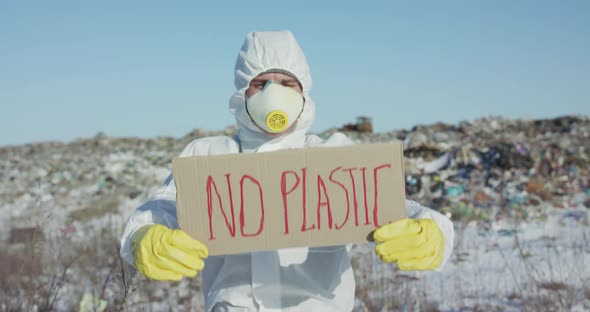 Portrait of Man Wore in Protective Suit Show Protest Sign "No Plastic" at Camera alt