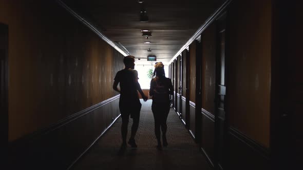 Back View of Caucasian Young Couple Walking Hotel Hallway