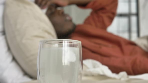 AfricanAmerican Black Man Lies in Bed with a High Fever and Takes Antipyretics alt