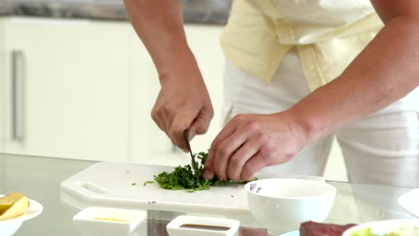 Close Up Man Cooking at Home, Cuts Fresh Parsley for Salad Dressing on Kitchen