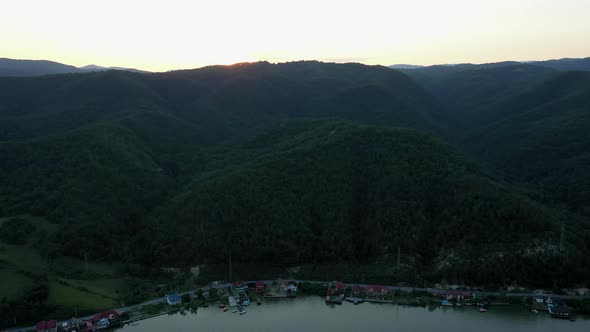 Aerial Shot of Beautiful Sunset in Carpathian Mountains Green Forest in Dusk and a Small Village on