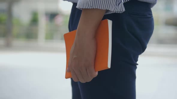 Close up caucasian businessman hand holding a book on the street urban city.