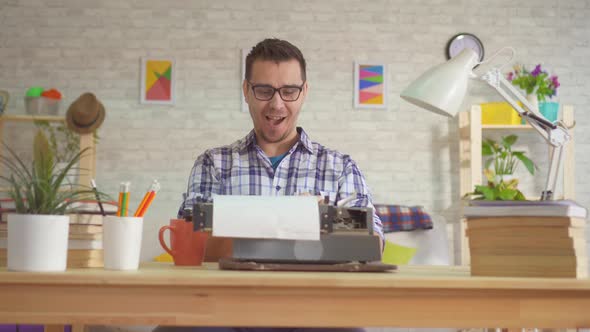 Portrait of a Young Man Writer Typing Enthusiastically on an Old Typewriter alt