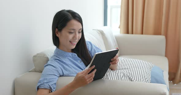 Woman look at tablet computer and sit on sofa at home
