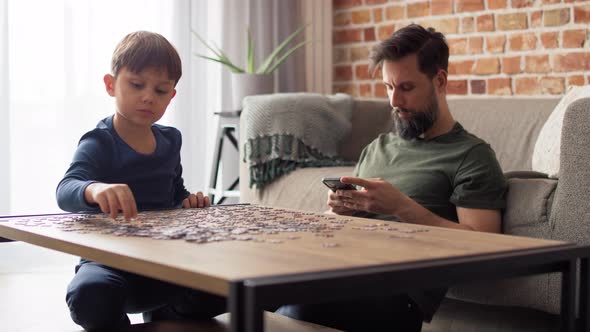 Video of boy solving jigsaw puzzle during father using phone. Shot with RED helium camera in 8K. alt