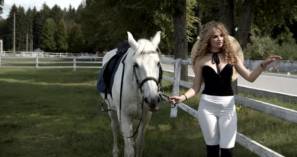 Young Jockey Walks With A Horse In The Meadow alt