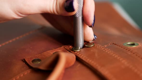Female Worker Puts Rivets on Leather Bag Straps with Chisel and Hummer. Crafted Handmade alt