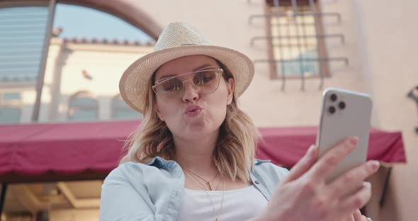 Portrait of Attractive Woman Is Smiling When Making Selfie on White Smartphone alt