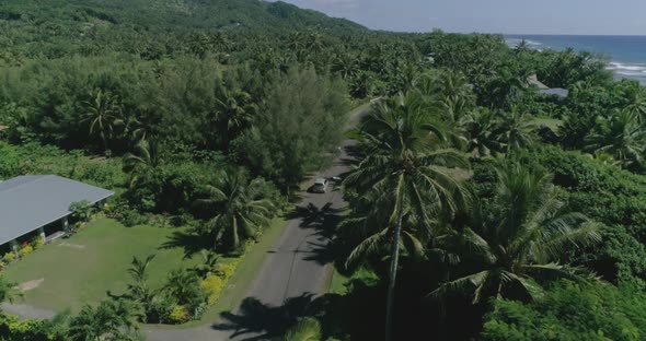 Drone Follows Two Cars Moving the Exotic Road Along the Ocean in Cook Islands