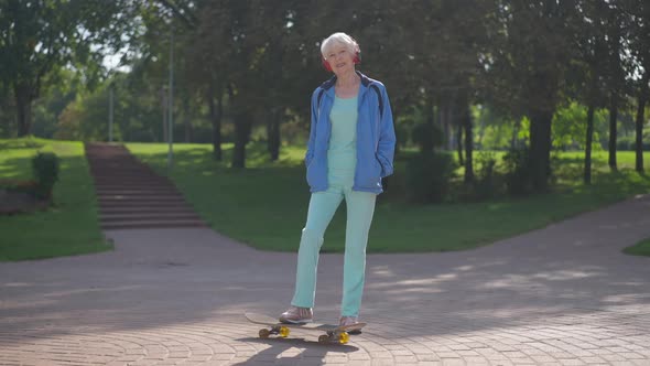 Happy Confident Senior Sportswoman Putting Foot on Skateboard Smiling Looking Away alt