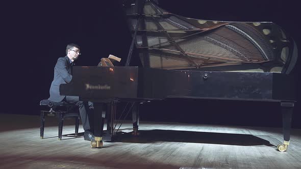 Pianist Playing the Grand Piano on Big Stage in Concert Hall with Dimmed Light