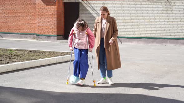 Mom Helps Daughter Learn To Walk On Crutches Stock Footage Videohive