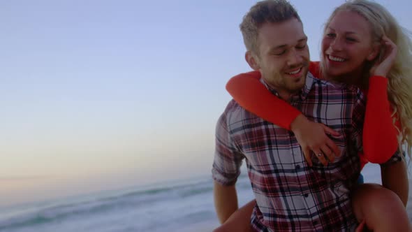 Man giving piggyback woman at beach 4k