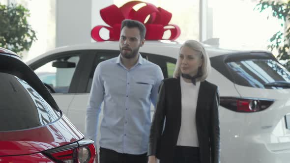 Young Couple Choosing Automobile To Buy at Car Dealership