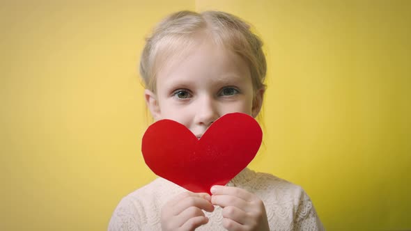 Little girl with valentine on yellow background