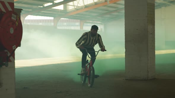 BMX riders in an empty warehouse using smoke grenade alt