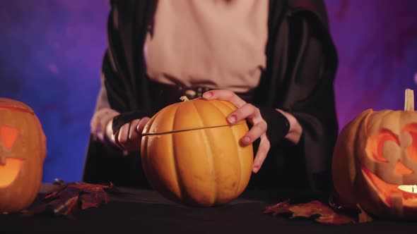 A witch carves a pumpkin for halloween. Beautiful lighting. Halloween!