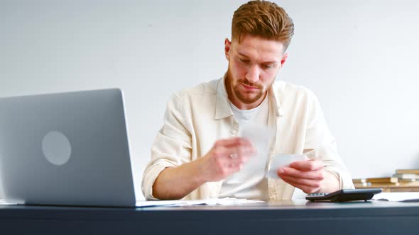 Bearded company analyst in analyzes sums in paper invoice receipts alt