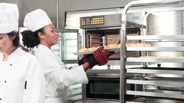 Female chef in uniform prepare to bake bread and pastry in stainless kitchen. alt