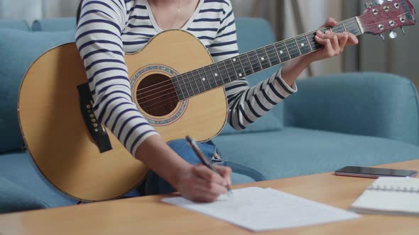 Woman Composer Playing A Guitar And Composing Music On Paper At Home alt
