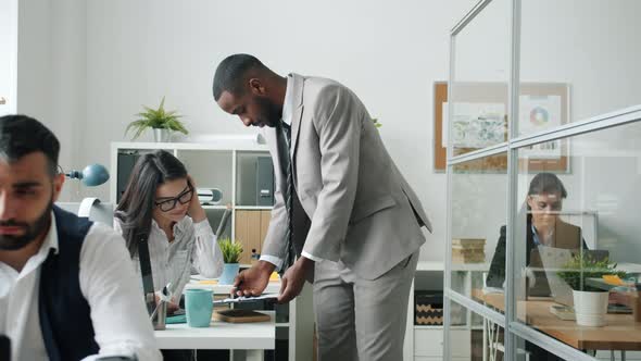 AfroAmerican Man Talking to Asian Colleague Then Dancing Having Fun in Office alt