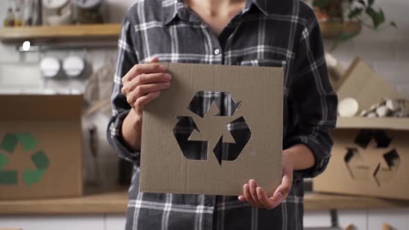 Processing Of Raw Materials Of Products. Girl Holding A Recycling Sign Stands Against The Background alt