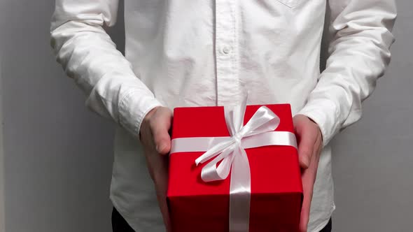 A young man in a white shirt gives a gift a white background