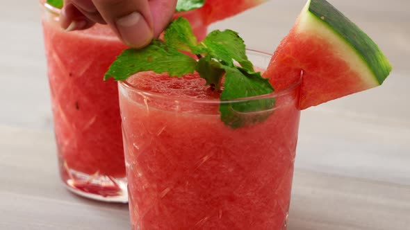 Healthy homemade watermelon fruit smoothies in the glasses being garnished with peppermint leaves