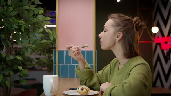 Attractive Casually Dressed Girl Enjoys Taste of Delicious Cake in Cafe