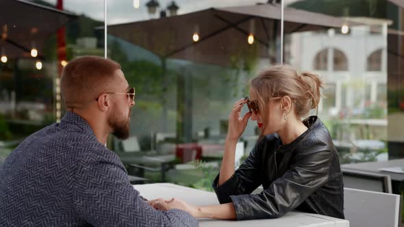 a Couple is Sitting at a Cafe Table on the Street alt