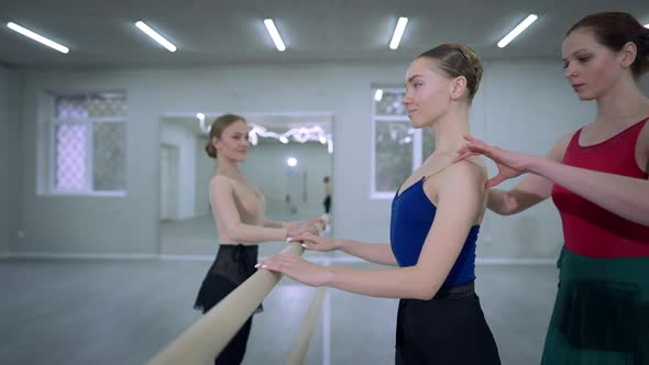 Agile Young Woman Standing at Barre with Confident Professional Ballet Master Adjusting Shoulders alt