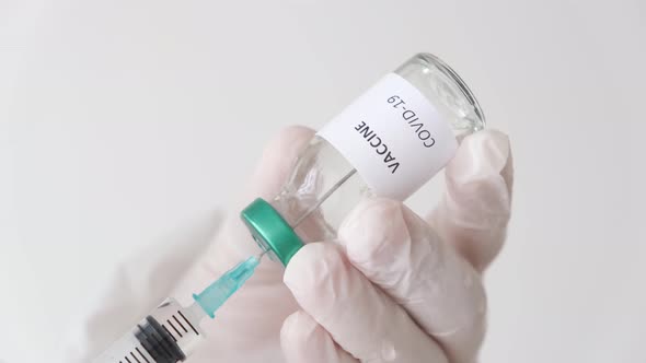 Doctor holding the covid-19 vaccine with his fingers. Vaccine and syringe in hand