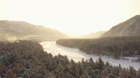 Scenery Aerial View of Winter Forest and Frozen River Katun on a Sunset Against Mountains alt