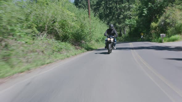 Tracking shot of man riding motorcycle on country road.  Fully released for commercial use.