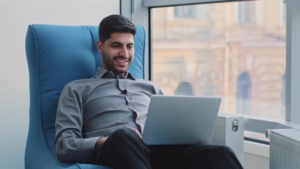 Happy Millennial Indian Corporate Employee in Creative Profession Sits in Comfortable Armchair in alt