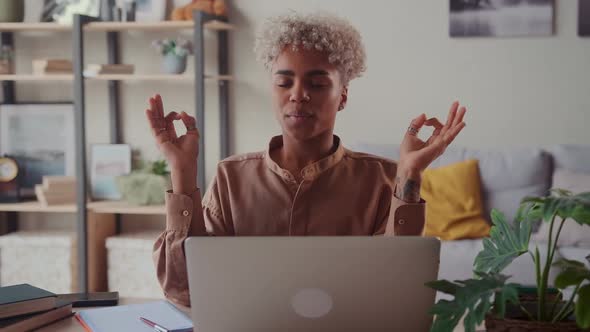 African American Woman Near Laptop Practicing Meditation at Home Office Desk alt