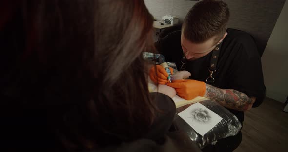 Tattoo Artist Draws a Picture on the Hand of a Young Woman, the Process of Creating a Tattoo. Slow alt