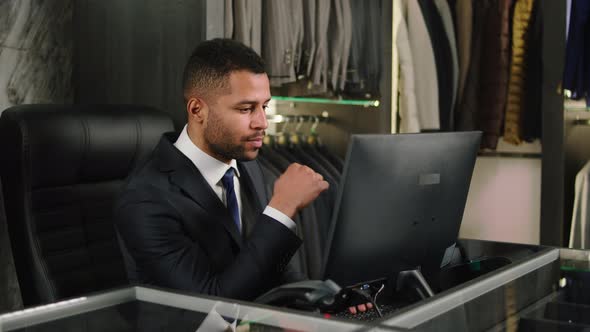 Man in the Suit Shop Working at the Computer He