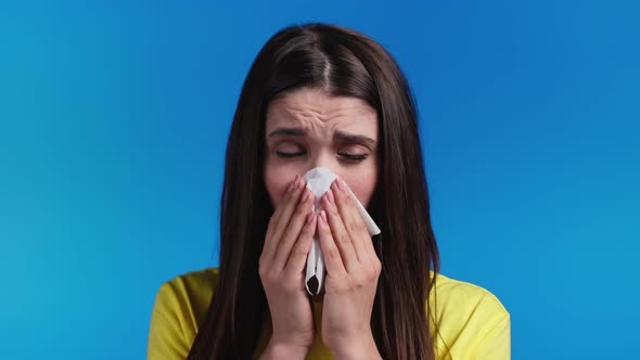 Ill Woman Sneezes Into Tissue alt