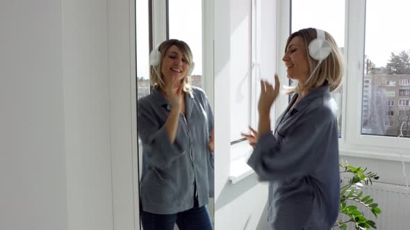 Portrait of cheerful european woman in headphones listening to music