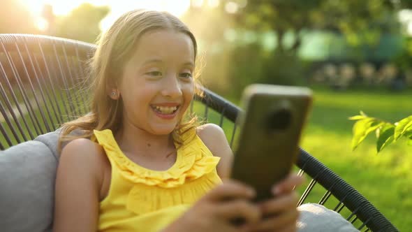 Happy kid girl holding smartphone having video call with friend distantly,