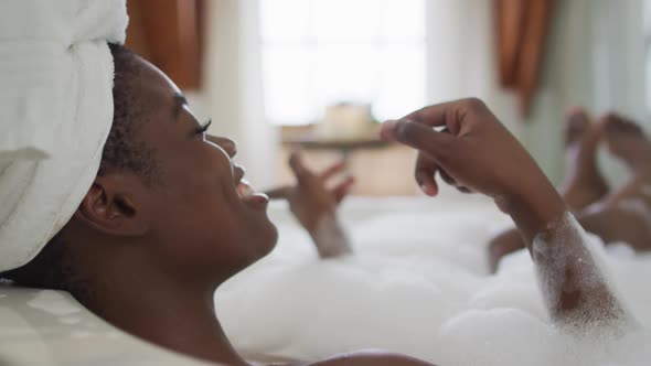 Profile of african american attractive woman relaxing in bath and singing in bathroom alt