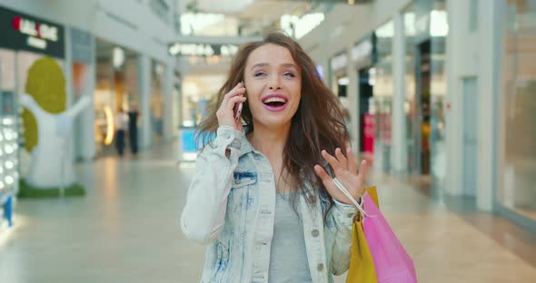 The Woman is Talking Emotionally on the Phone and Walking Through the Shopping Center alt