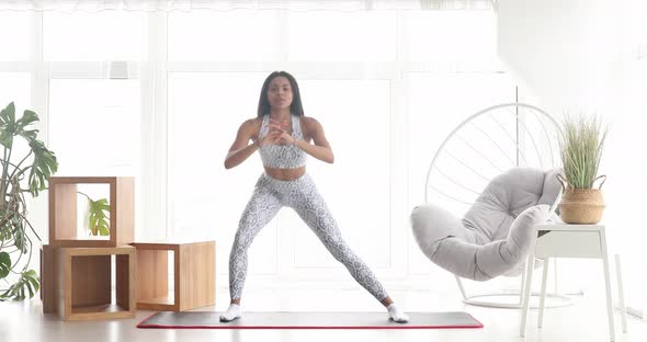 Athletic fit girl doing fitness aerobic exercises for booty in living room. alt