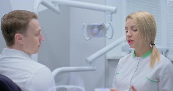 Beautiful Woman Dentist Consults a Patient in a Modern Office of a Dental Clinic alt