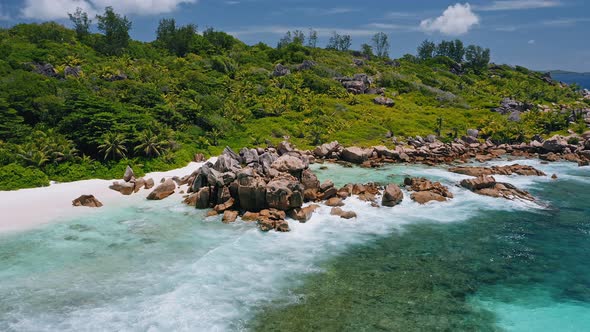 Aerial Circle Footage of Huge Granite Rocks and Ocean Waves in Lagoon of Anse Coco Tropical Paradise alt