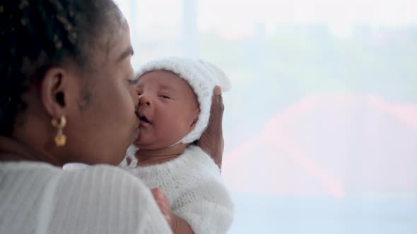 Close up African American mother hold or carry her newborn baby over shoulder and the kiss