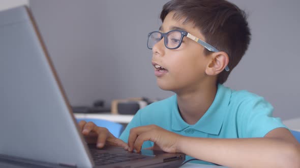 Focused Schoolboy Sitting at Desk in Classroom alt